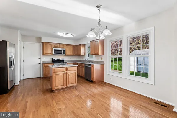 a kitchen with stainless steel appliances granite countertop a refrigerator a stove a sink dishwasher a oven with white cabinets and wooden floor