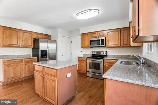 a kitchen with granite countertop a stove top oven a sink a counter top space and cabinets