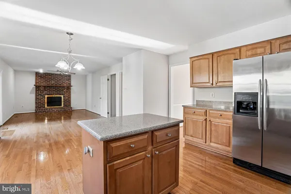 a kitchen with kitchen island granite countertop a stove a sink dishwasher and a refrigerator with wooden floor