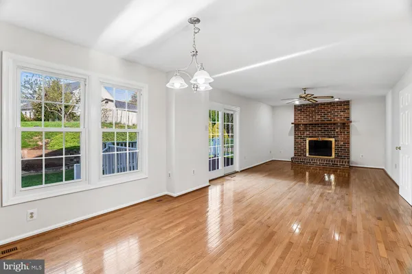 a view of an empty room with wooden floor fireplace and a window