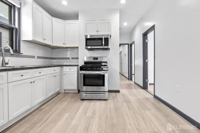 a kitchen with granite countertop a stove a sink and a microwave