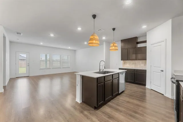 a kitchen with stainless steel appliances granite countertop a sink a stove and a wooden floors