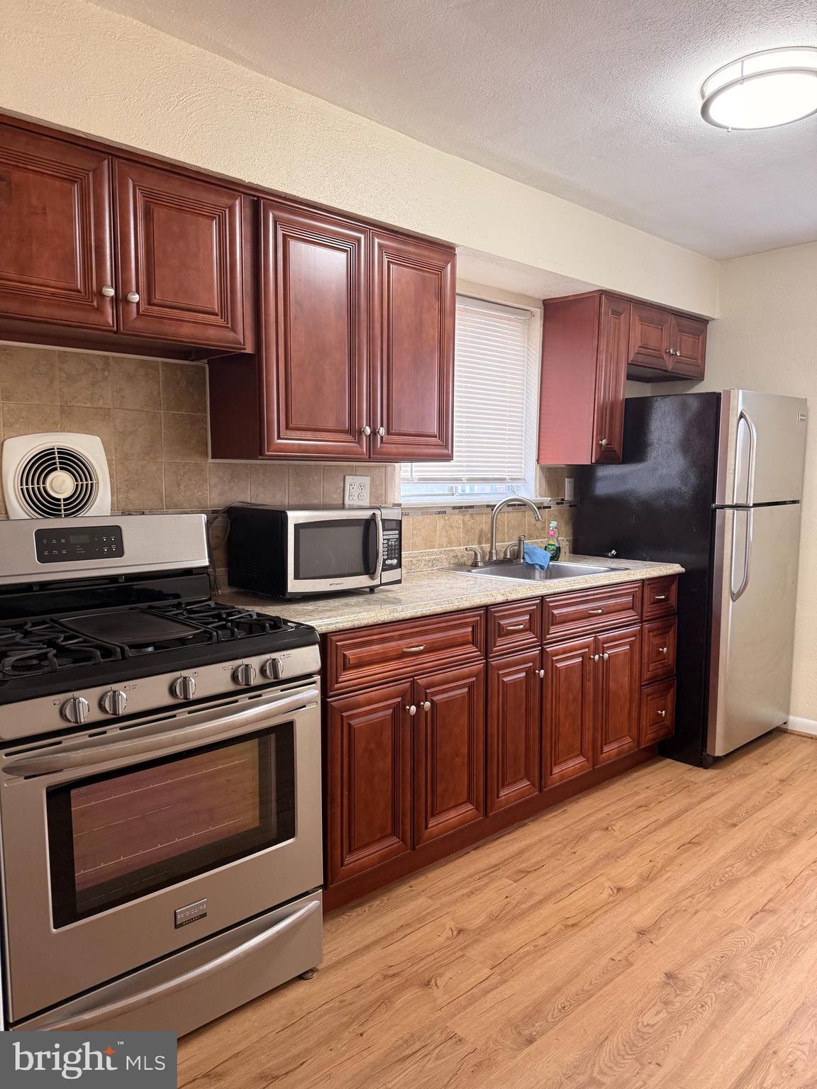 216 Boro Road, Unit A Secane, PA 19018 - Photo 10 of 26 a kitchen with stainless steel appliances granite countertop a stove top oven a sink dishwasher and a refrigerator with wooden cabinets