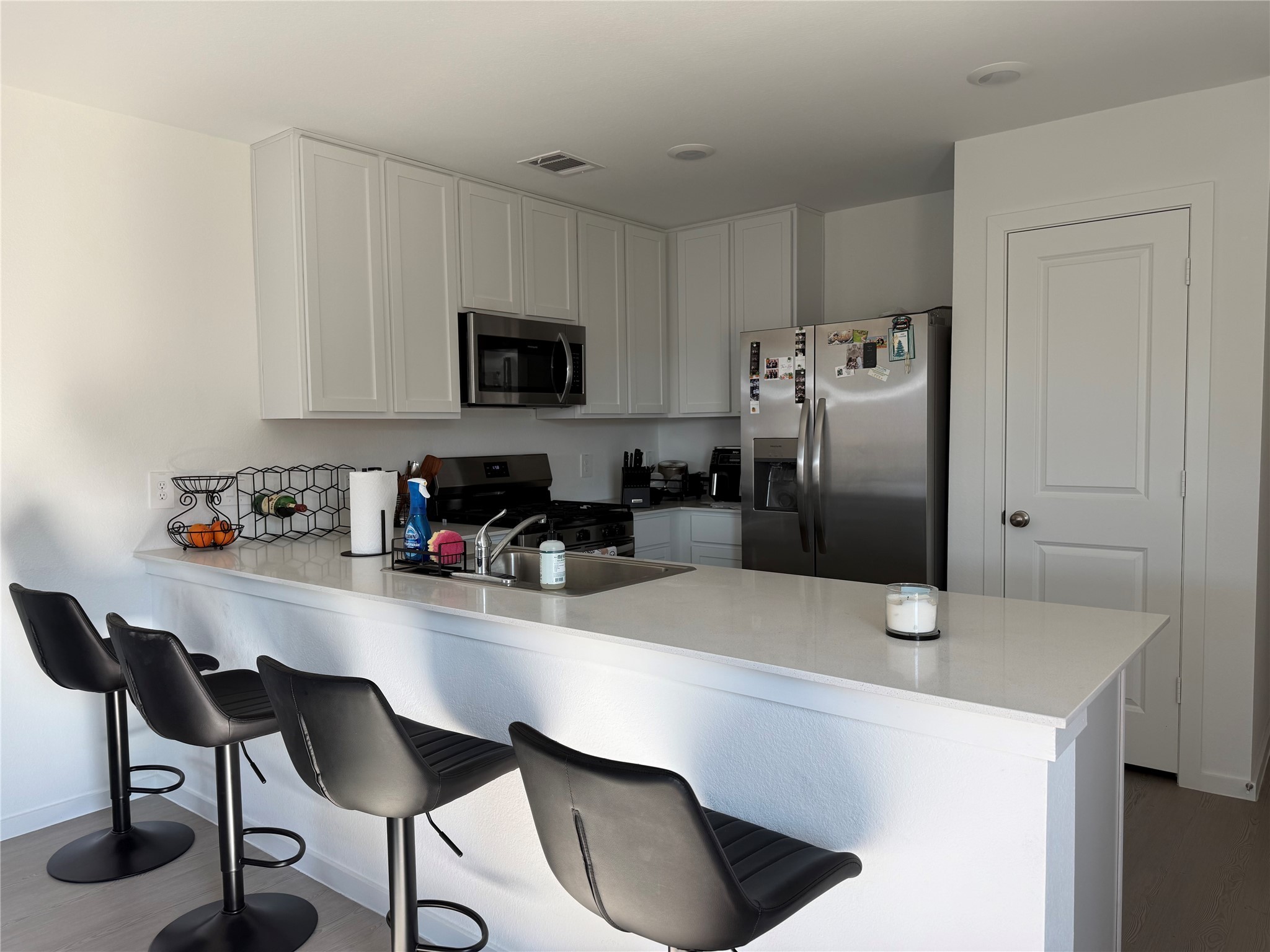 16722 Largetooth Aspen Lane New Caney, TX 77357 - Photo 22 of 37 a kitchen with granite countertop a refrigerator a stove a sink and white cabinets with wooden floor