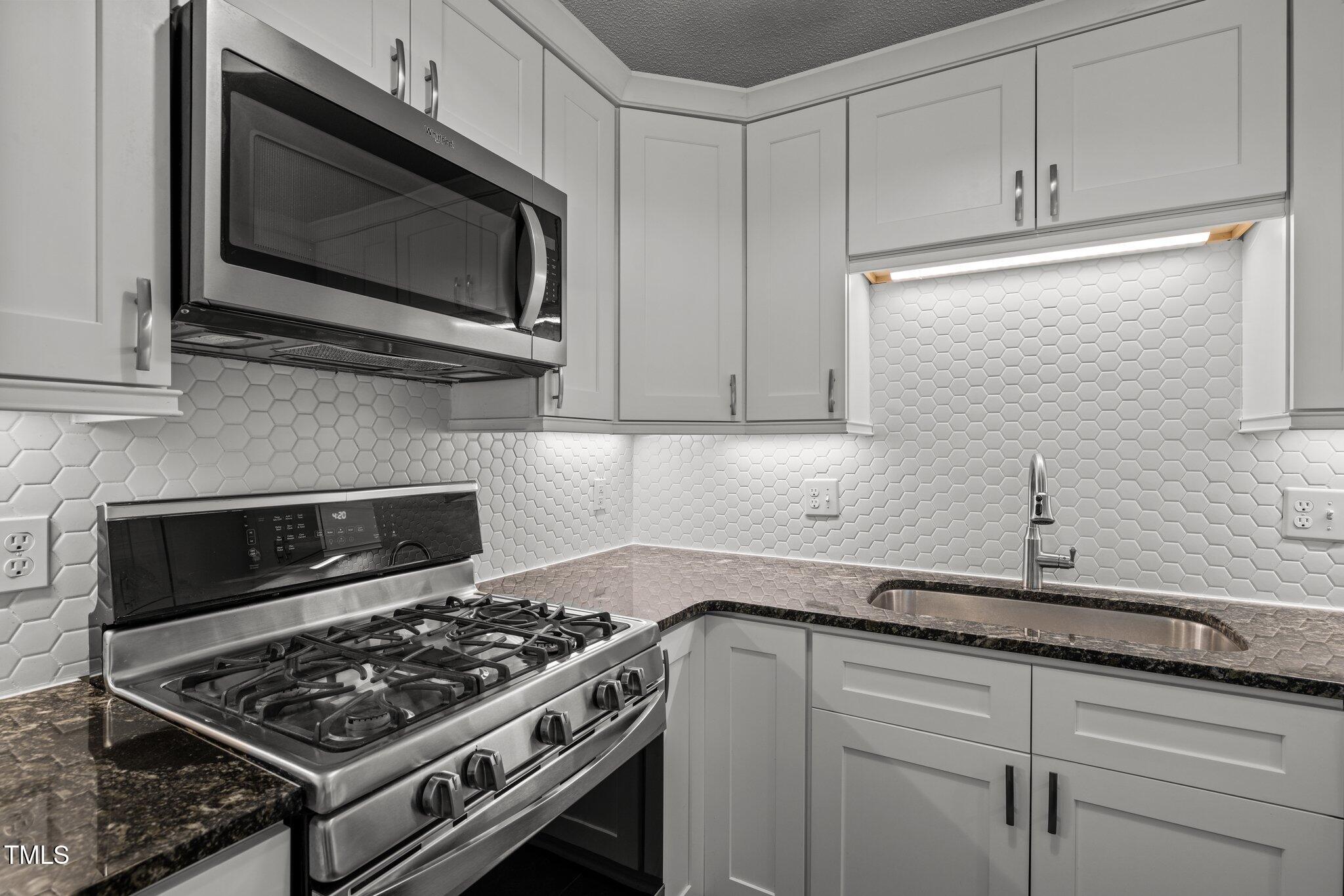 1040 Mills Street Raleigh, NC 27608 - Photo 5 of 21 a kitchen with stainless steel appliances a stove and a microwave