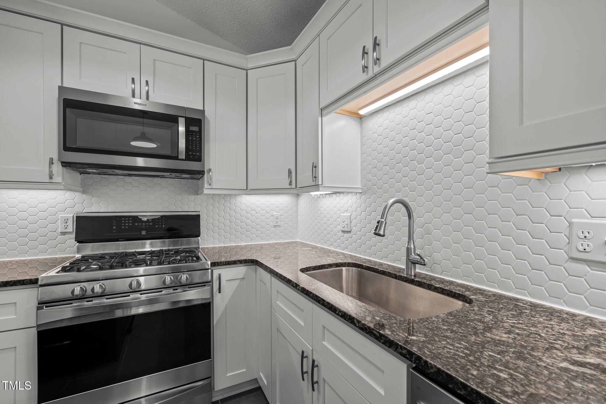 1040 Mills Street Raleigh, NC 27608 - Photo 6 of 21 a kitchen with granite countertop a sink a stove and microwave