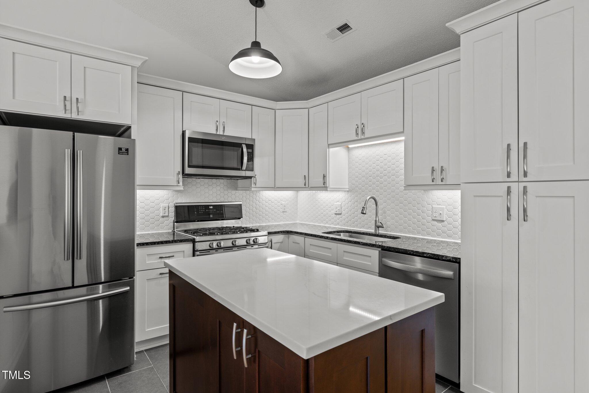 1040 Mills Street Raleigh, NC 27608 - Photo 7 of 21 a kitchen with stainless steel appliances granite countertop a refrigerator a sink a stove and white cabinets