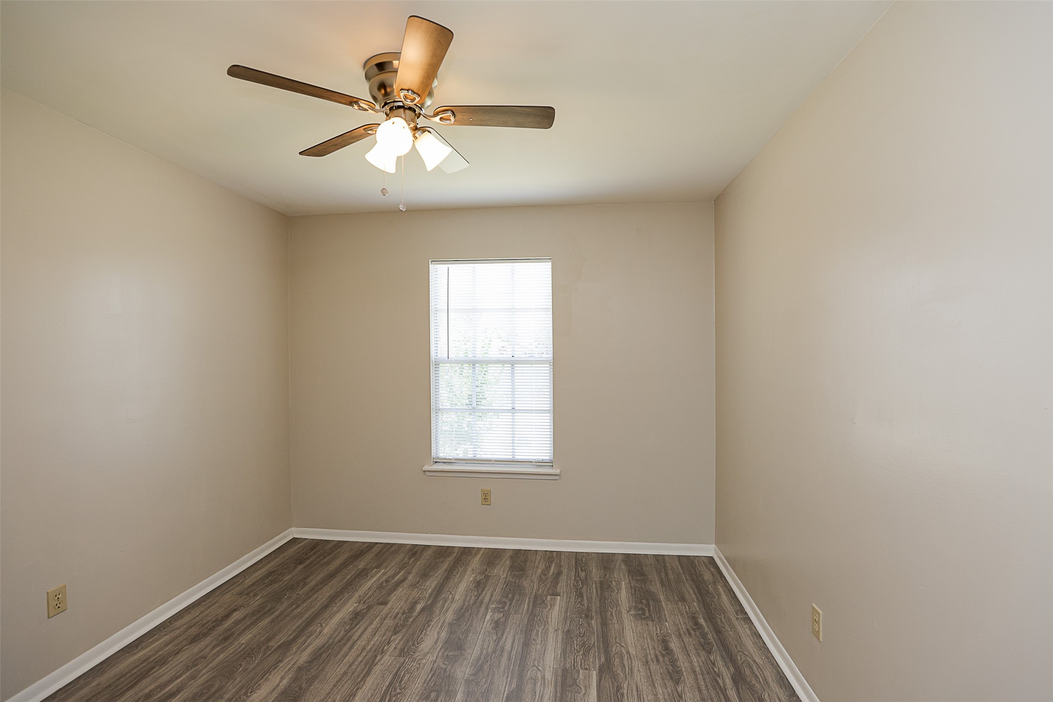 7810 Queen Street Houston, TX 77028 - Photo 11 of 21 This is a well-lit, primary bedroom with neutral walls, wood-look flooring, and a ceiling fan.