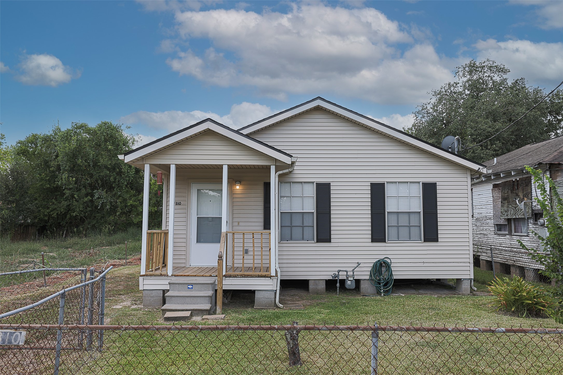7810 Queen Street Houston, TX 77028 - Photo 2 of 21 This is a single-story, traditional-style home featuring a covered front porch, beige siding, and contrasting black window shutters.