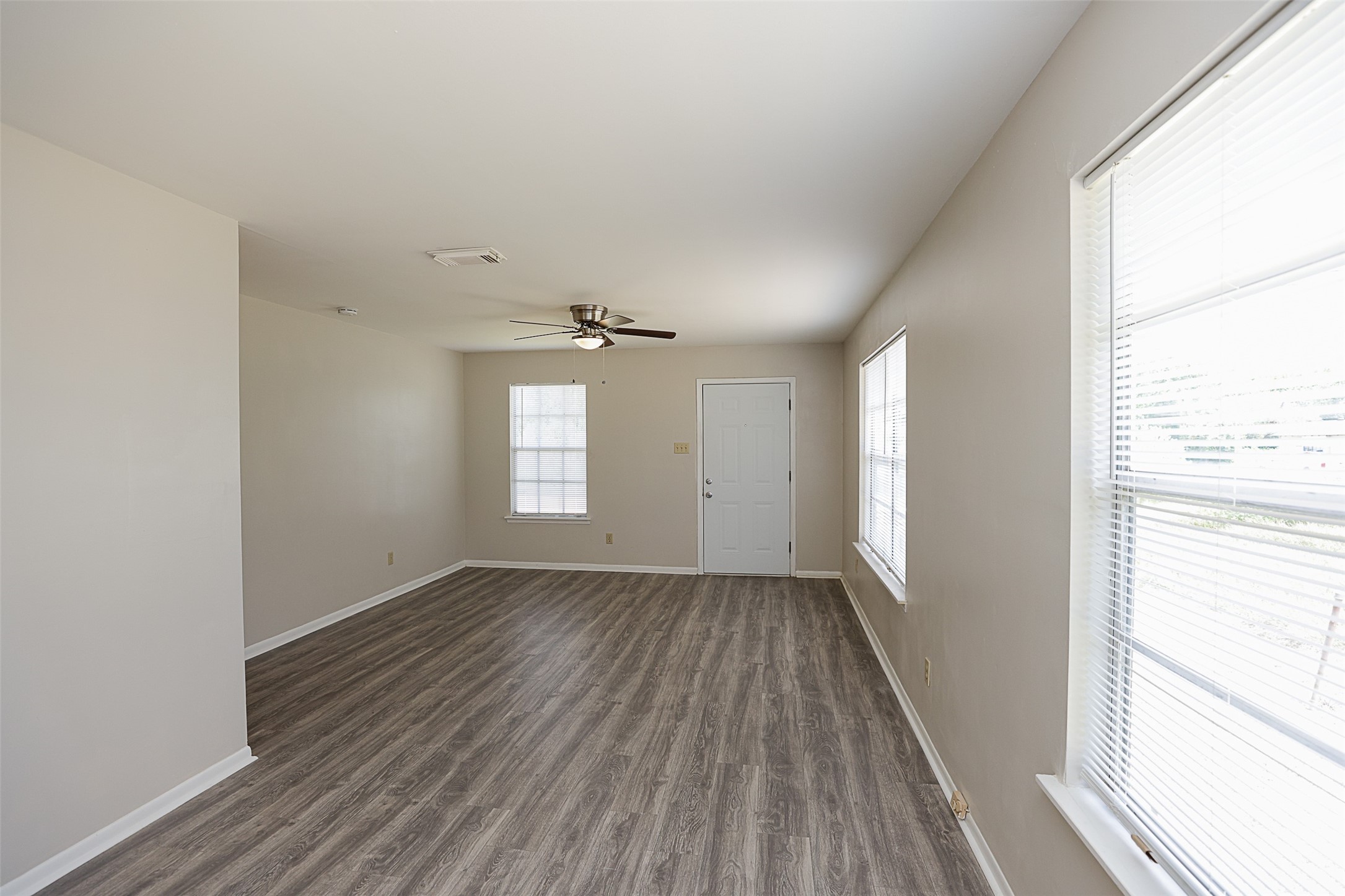 7810 Queen Street Houston, TX 77028 - Photo 6 of 21 This is a bright, spacious dining and living room with contemporary wood-look flooring, neutral wall colors, and ample natural light from two windows. It features a modern ceiling fan and a clean, white front door.