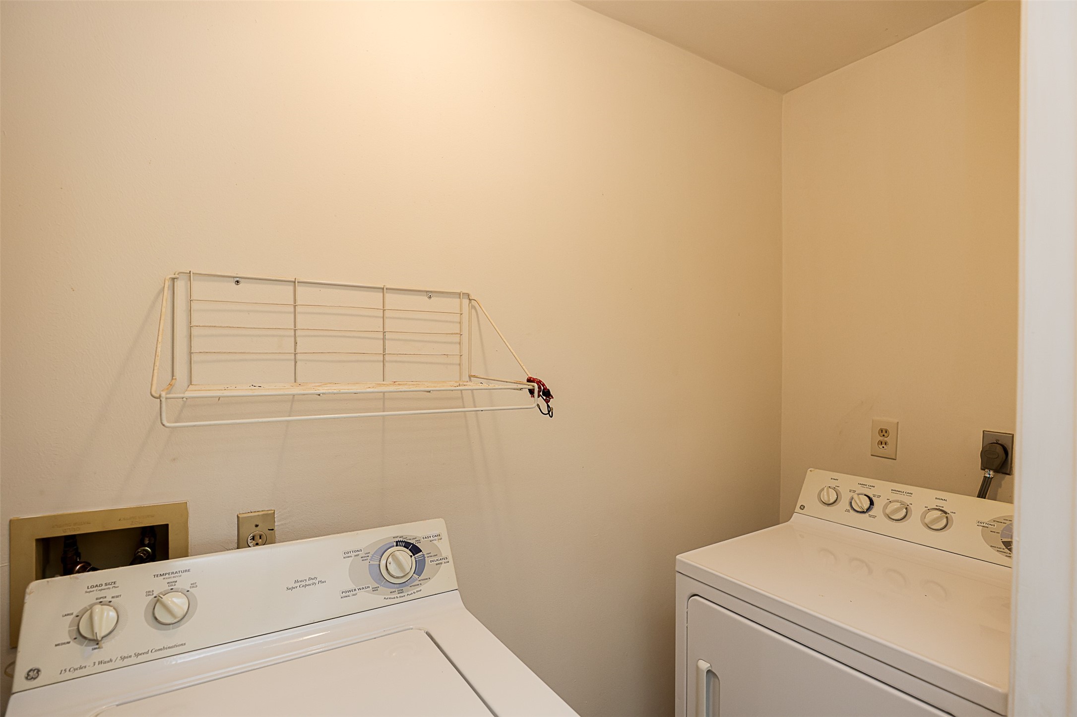 7810 Queen Street Houston, TX 77028 - Photo 10 of 21 This laundry area features a washer and dryer, and it includes a wall-mounted shelf.