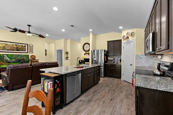 a kitchen with granite countertop a sink a counter top space stainless steel appliances and cabinets