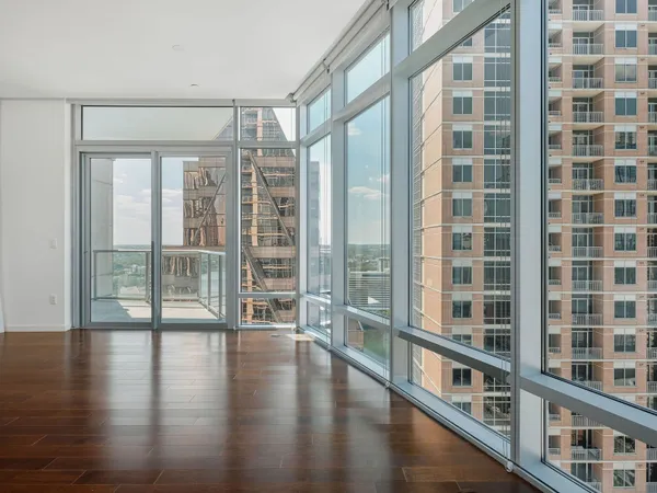 a view of an empty room with wooden floor and windows