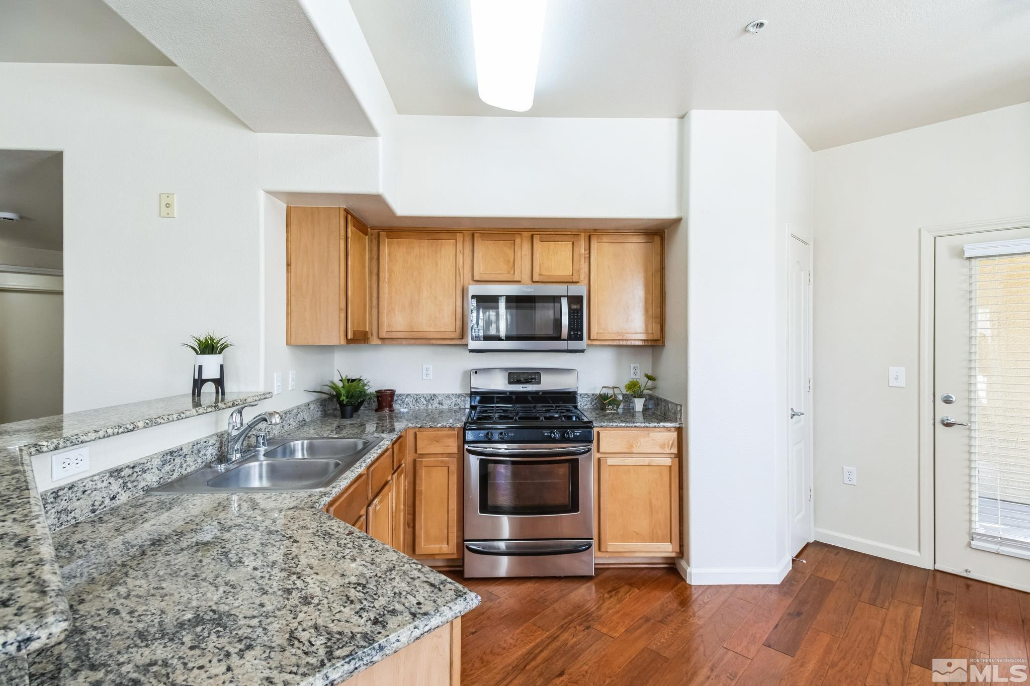 9050 Double R Boulevard, Unit 1412 Reno, NV 89521 - Photo 5 of 18 a kitchen with stainless steel appliances granite countertop a stove a sink and a microwave