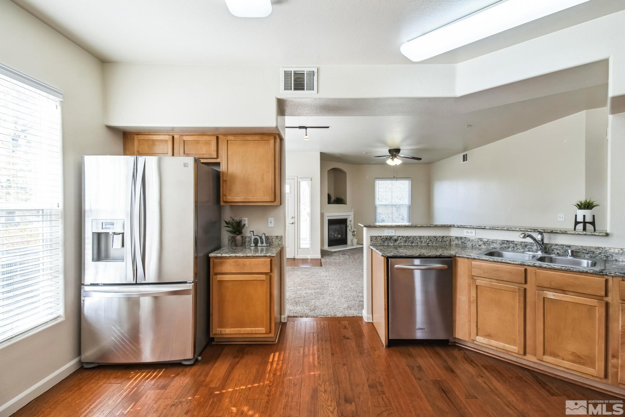 9050 Double R Boulevard, Unit 1412 Reno, NV 89521 - Photo 8 of 18 a kitchen with stainless steel appliances granite countertop a refrigerator a stove a sink and white cabinets with wooden floor next to windows