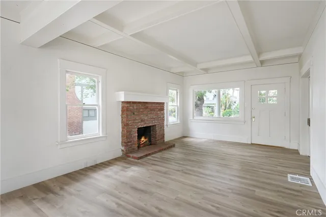 an empty room with wooden floor fireplace and windows