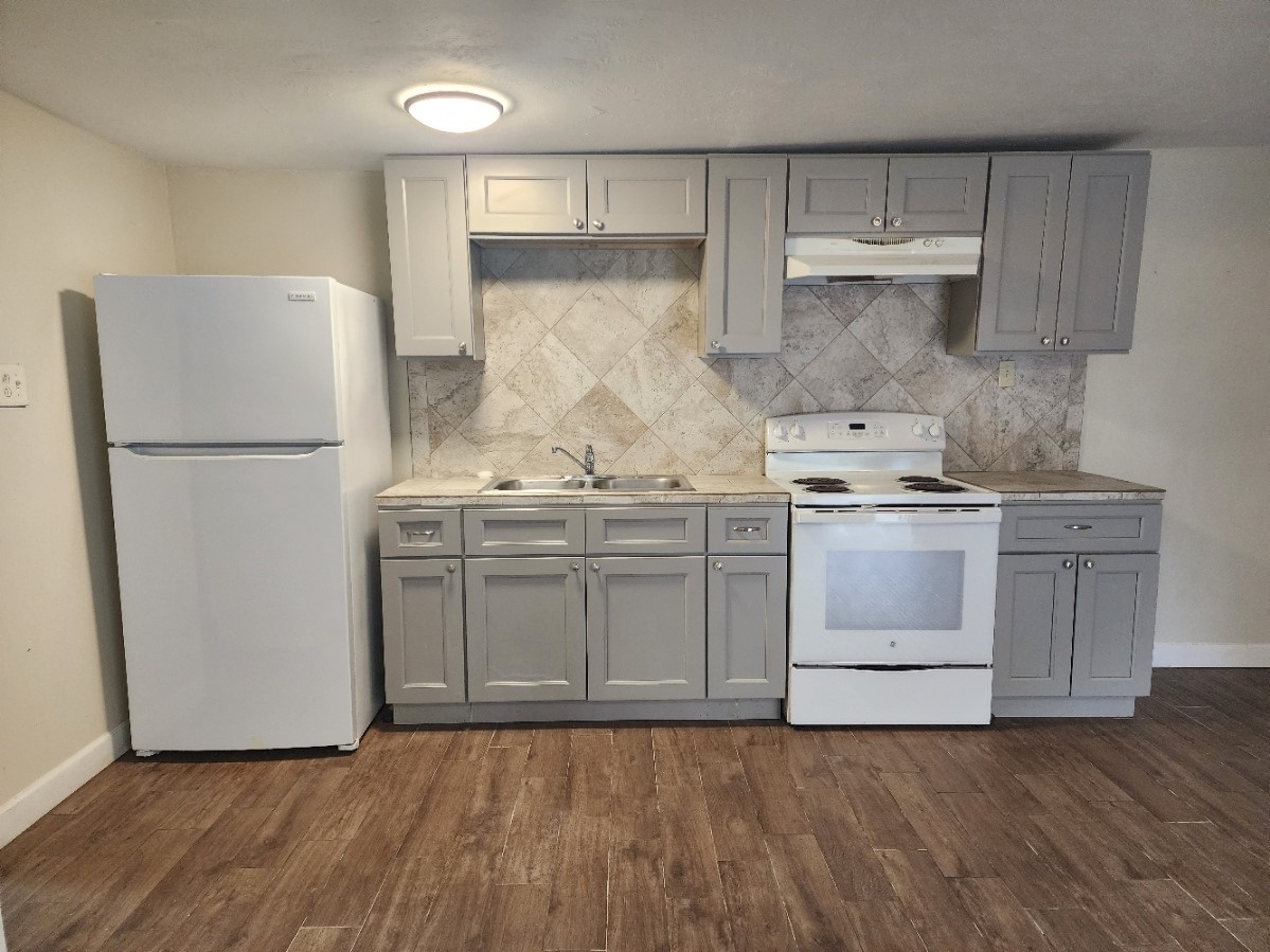 a kitchen with a stove a refrigerator and a white cabinets