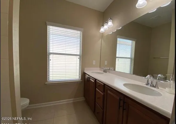 a bathroom with a granite countertop sink a toilet a large mirror and a window