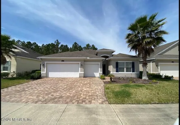 a front view of a house with a garden and trees