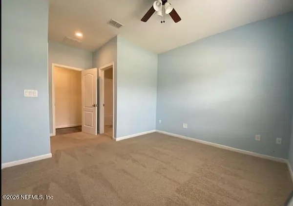 an empty room with ceiling fan and window