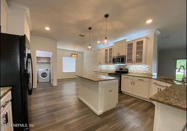 a kitchen with stainless steel appliances granite countertop a refrigerator a sink dishwasher a stove and white countertops with wooden floor