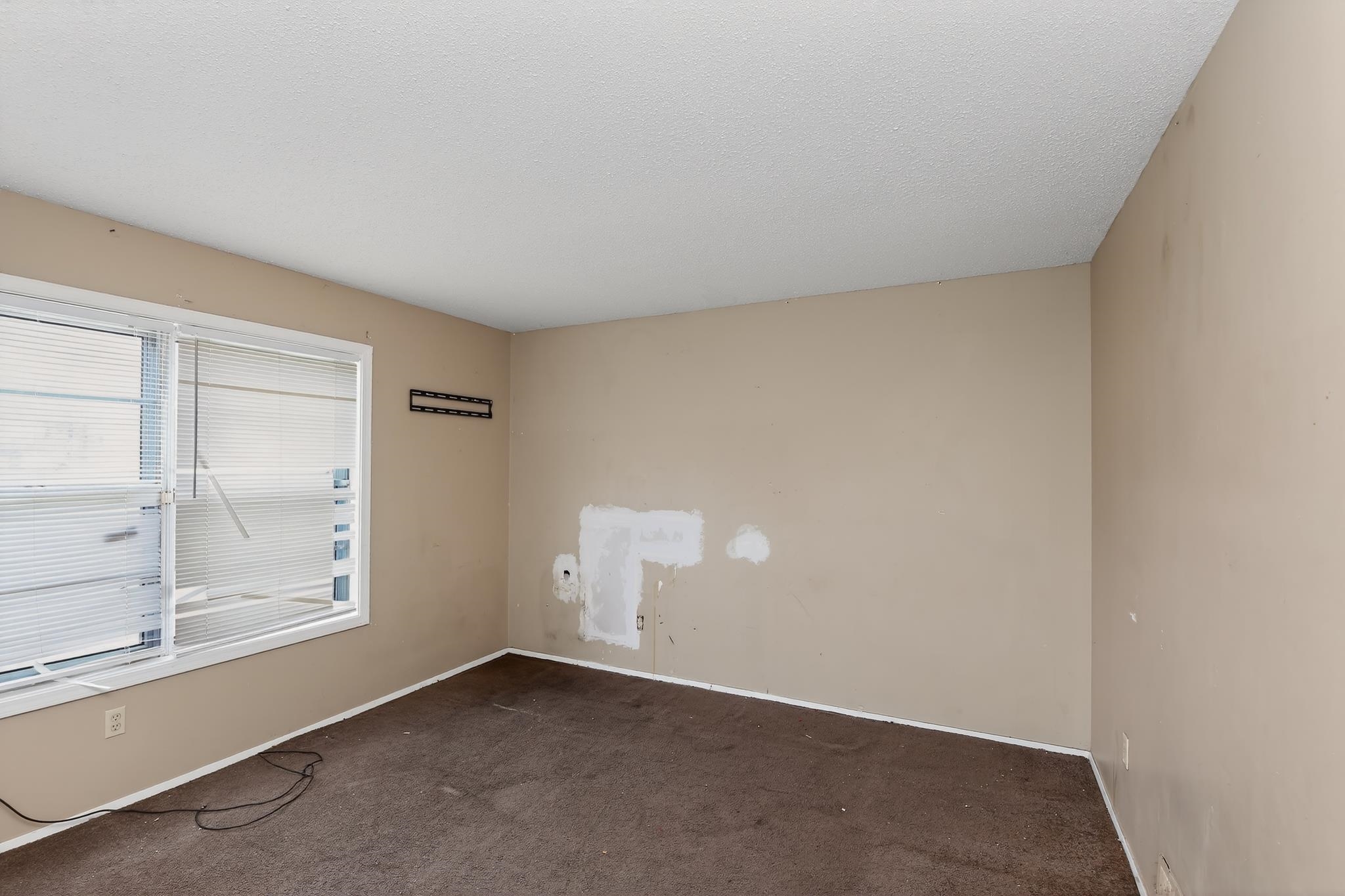 645 Parkrose Road Memphis, TN 38109 - Photo 29 of 32 Room featuring light-toned walls, textured ceiling, brown carpeting, and a white-trimmed window with horizontal blinds
