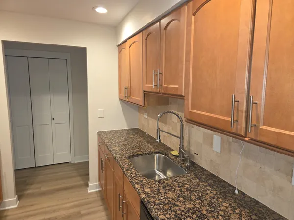 a kitchen with granite countertop a sink a stove and cabinets