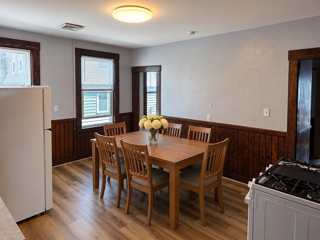 2 Hillside Street, Unit 3 Worcester, MA 01610 - Photo 6 of 30 a kitchen with granite countertop a refrigerator a stove a dining table and chairs with wooden floor