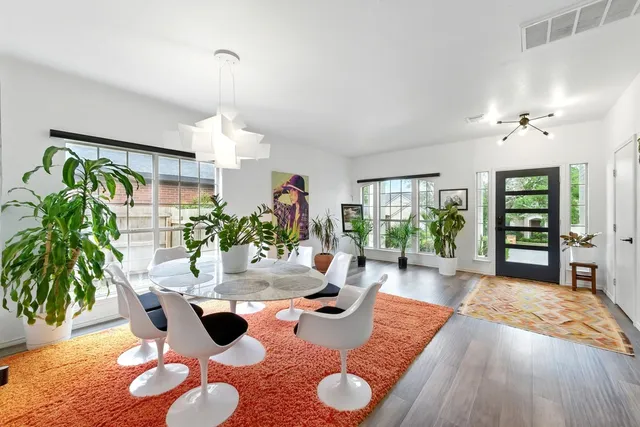 a dining room with wooden floor a chandelier a glass table and chairs