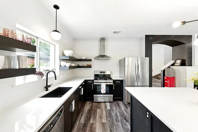 a kitchen with stainless steel appliances granite countertop a sink a stove and refrigerator