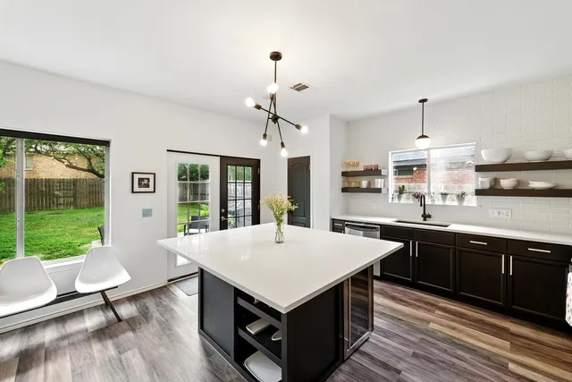 a kitchen with a stove a sink dishwasher and a dining table with garden view