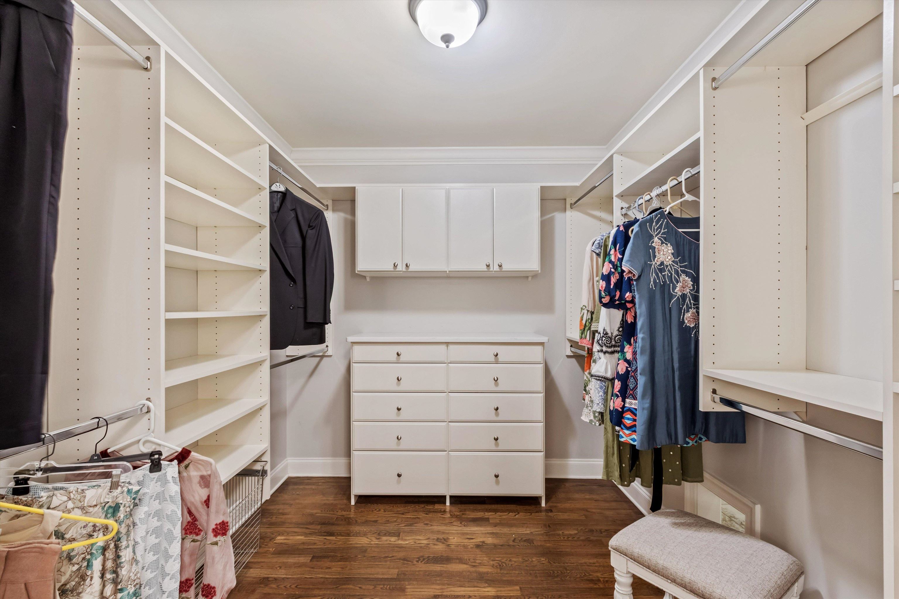 5302 South Angela Road Memphis, TN 38120 - Photo 23 of 40 Custom closet system featuring extensive shelving, multiple hanging rods, built-in dresser, upper cabinetry, and wood-finish flooring