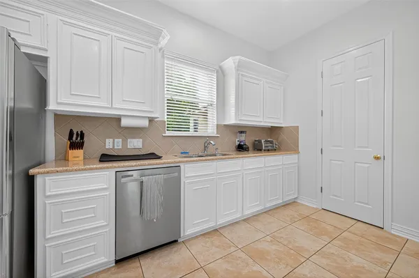 a kitchen with white cabinets and sink