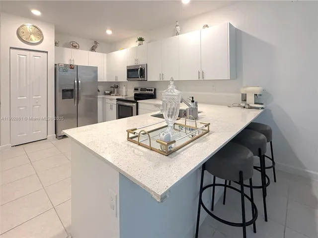 a kitchen with granite countertop a table chairs stove and refrigerator