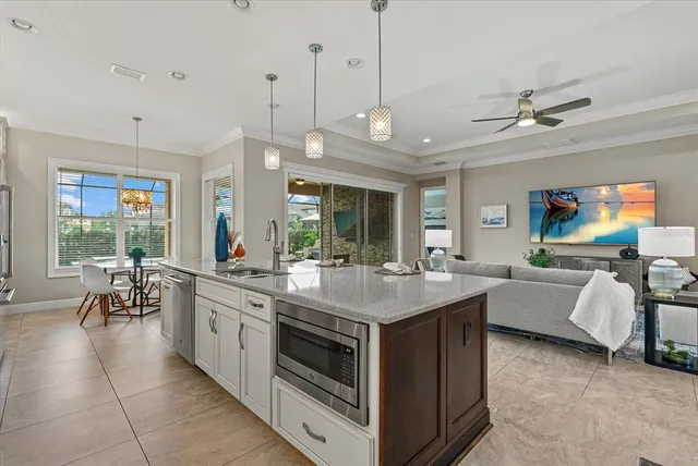 a kitchen with a stove a counter top space a sink and living room view