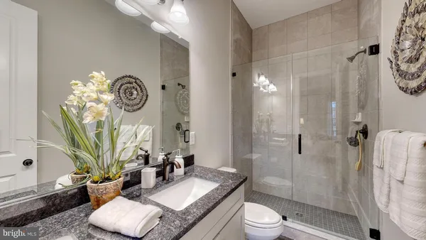a bathroom with a granite countertop sink a toilet and shower