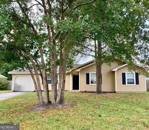 a backyard of a house with plants and large tree