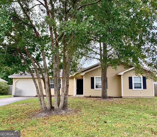 a backyard of a house with plants and large tree