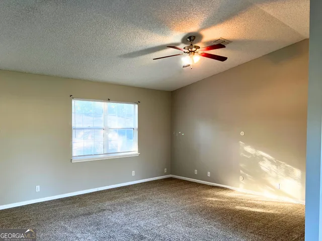 an empty room with windows and fan