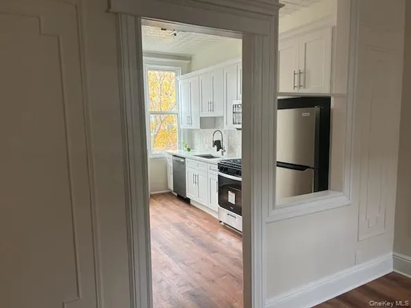 a view of a kitchen with white cabinets and refrigerator