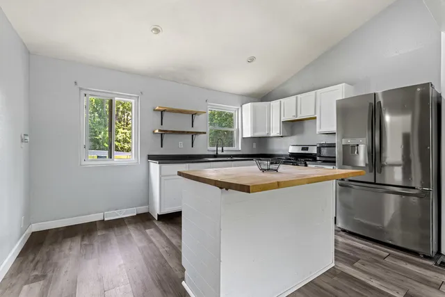 a kitchen with granite countertop a refrigerator and a stove top oven