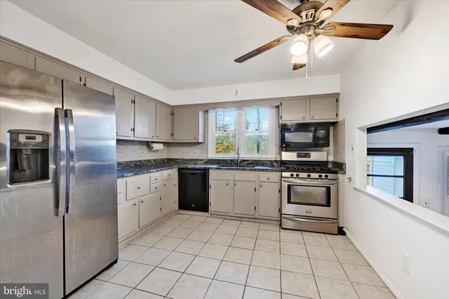 a kitchen with stainless steel appliances kitchen island granite countertop a refrigerator and a stove top oven