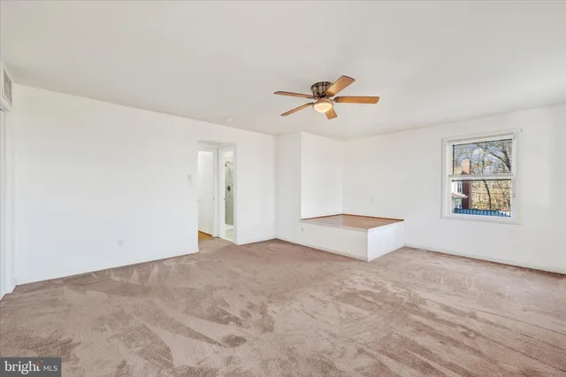 an empty room with windows and ceiling fan