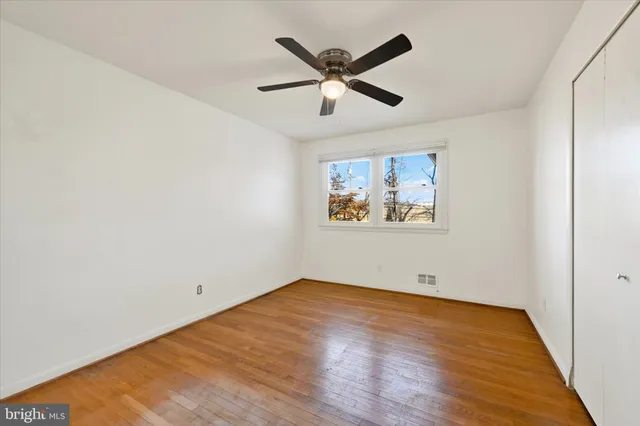 an empty room with wooden floor and ceiling fan