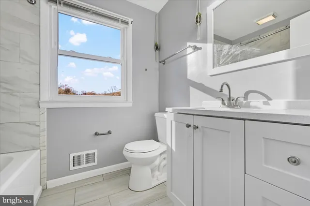 a bathroom with a granite countertop sink toilet and mirror