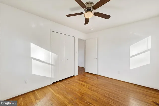 an empty room with wooden floor fan and windows