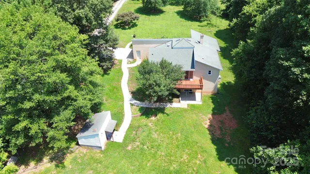 an aerial view of a house with a yard and trees all around