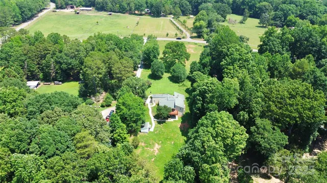 an aerial view of residential house with outdoor space and trees all around