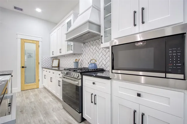 a kitchen with granite countertop a sink a counter space appliances and cabinets