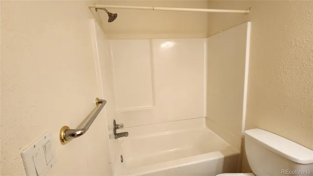 a bathroom with a granite countertop bathtub shower and toilet